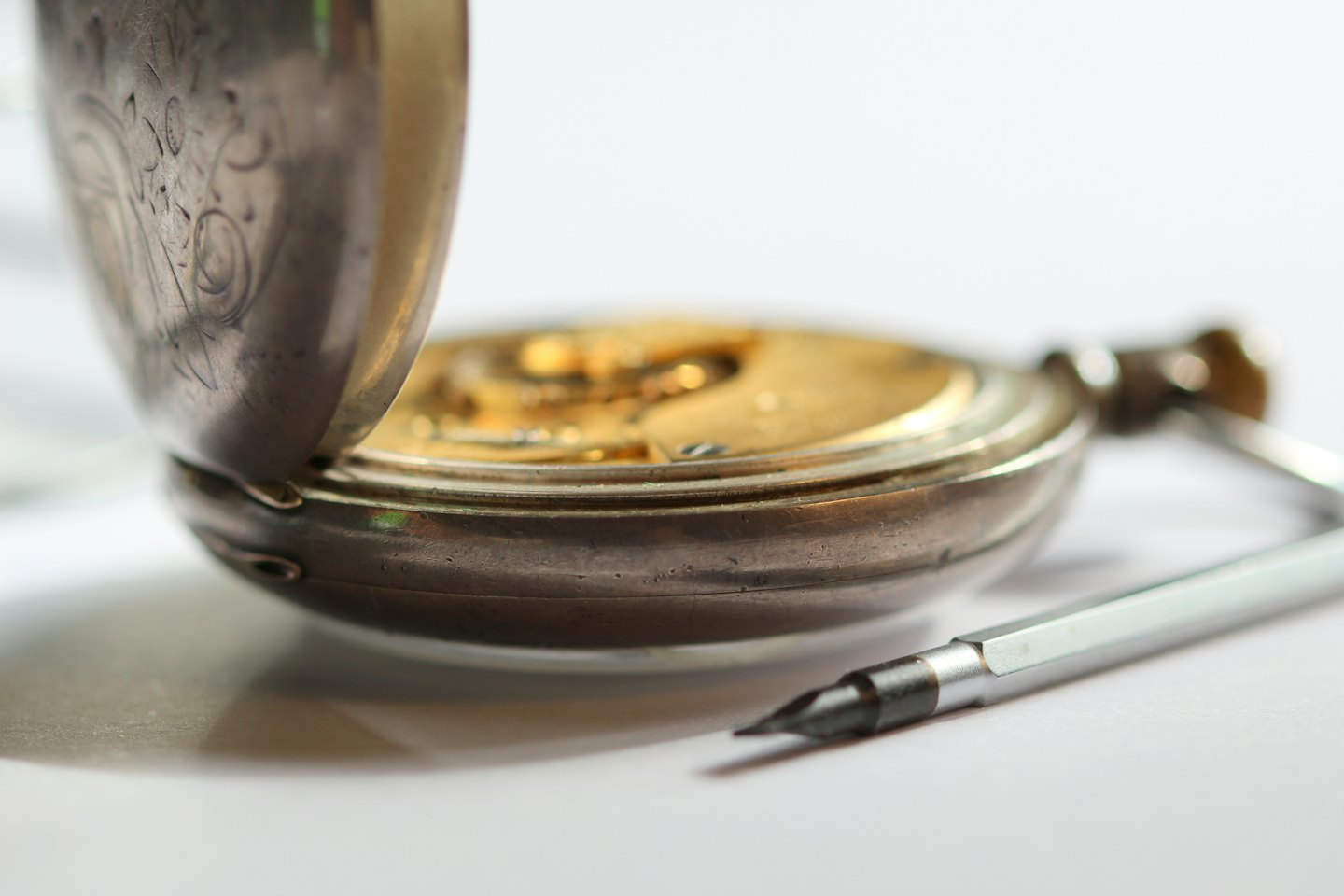 Orologio da tasca antico aperto per riparazioni con attrezzi.