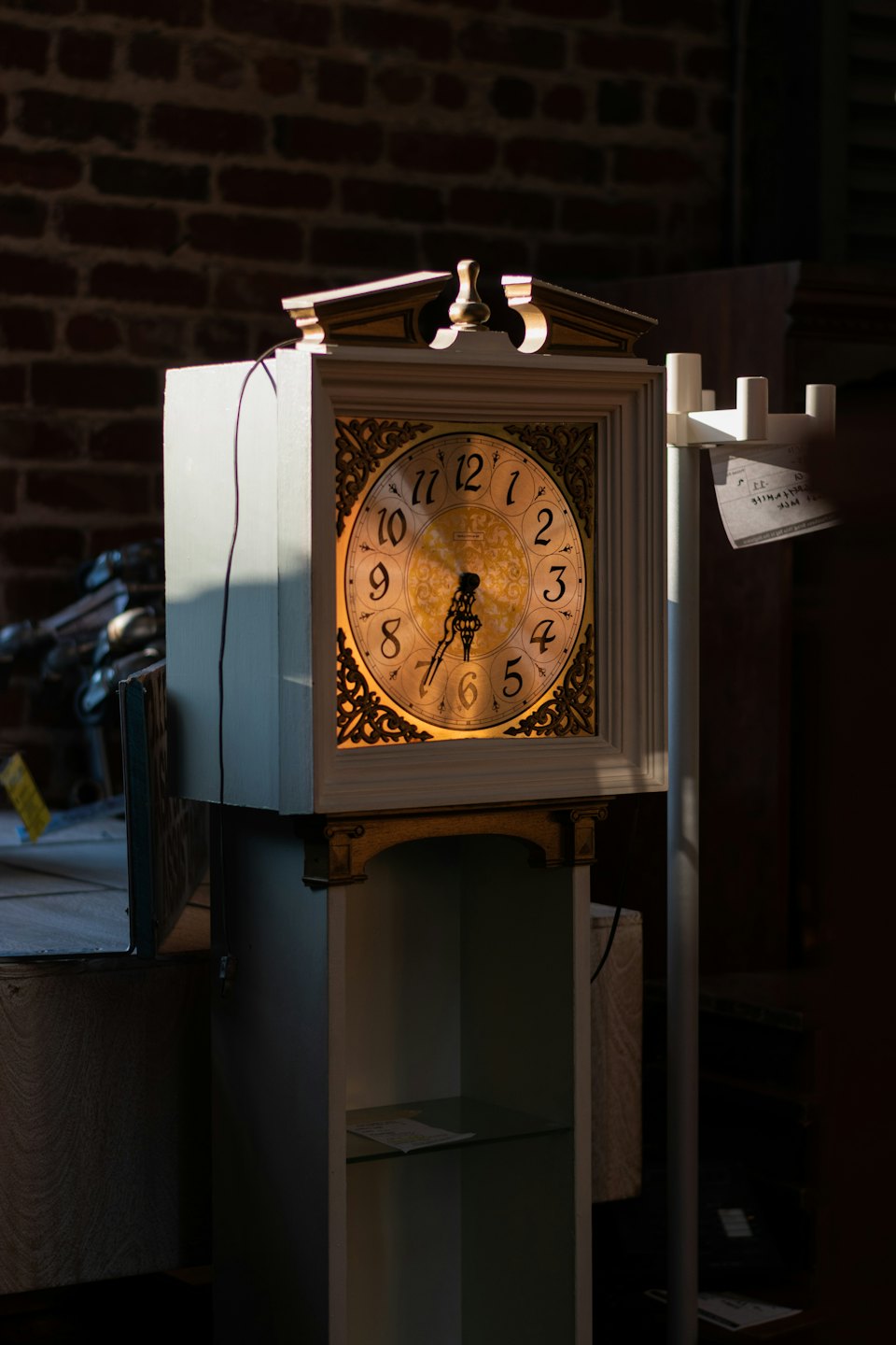 Orologio a pendolo antico con dettagli dorati su un muro di mattoni.
